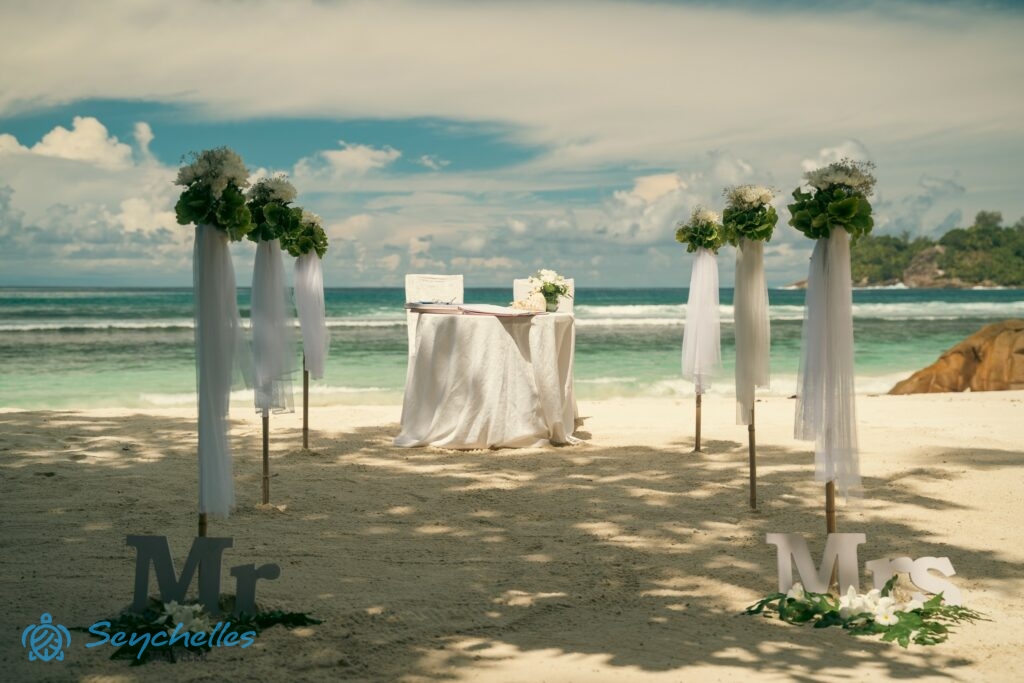 Fehér krizantém virágokkal díszített bevonuló folyosó és esküvői asztal Baie Lazare tengerparton.