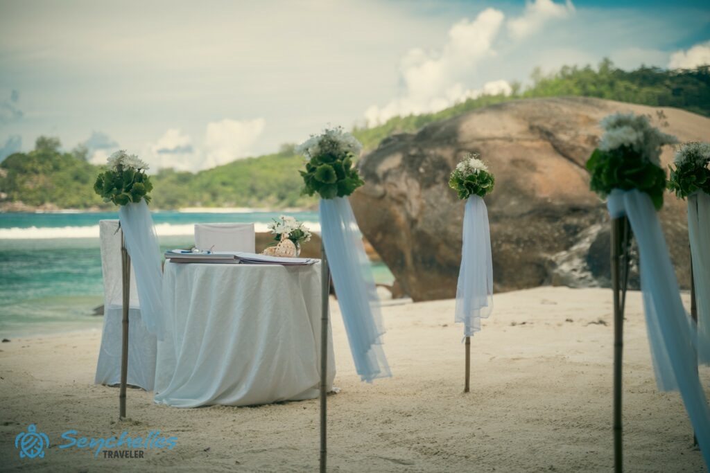 Fehér virágokkal, zöld levelekkel és fehér fátyollal díszített bevonuló folyosó Baie Lazare tengerparton.