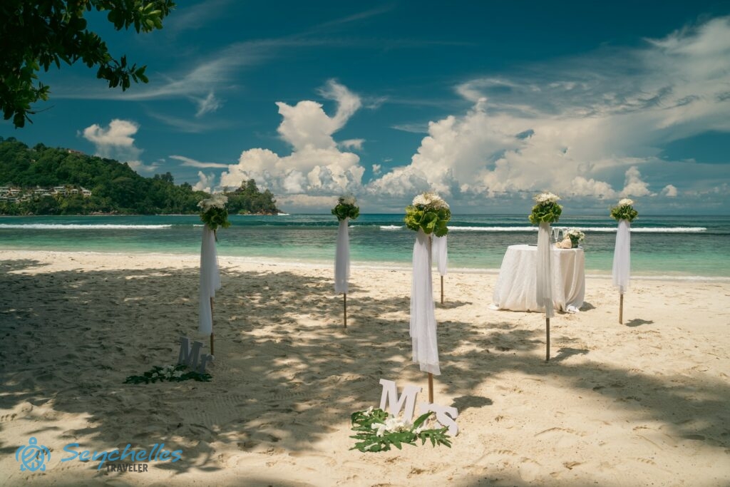 Feldíszített bevonuló folyosó és esküvői asztal pezsgőspoharakkal Baie Lazare tengerparton.