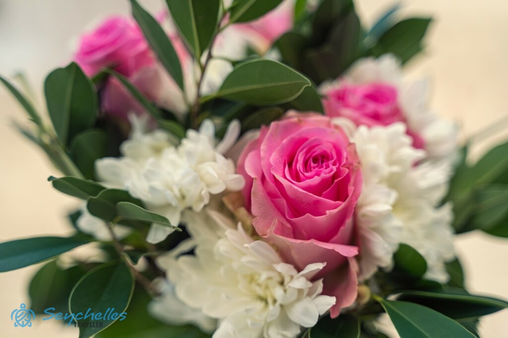 A bevonuló folyosót díszítő fehér krizantémok és élénk rózsaszín rózsák Baie Lazare tengerparton.