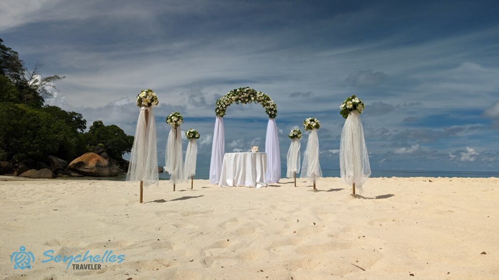 Íves boldogságkapu és bevonuló folyosó virágokkal és fehér muszlinnal díszítve, Anse Louis tengerparton.