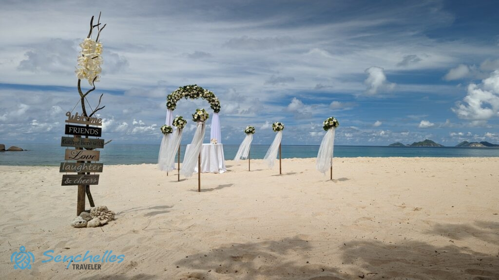 Dekorációs tábla, fehérrel díszített, íves boldogságkapu és bevonuló folyosó Anse Louis tengerparton.