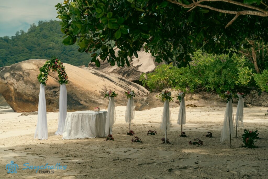 Feldíszített bevonuló folyosó, az oszlopok között homokba tűzött virágokkal, esküvői asztal és íves boldogságkapu.