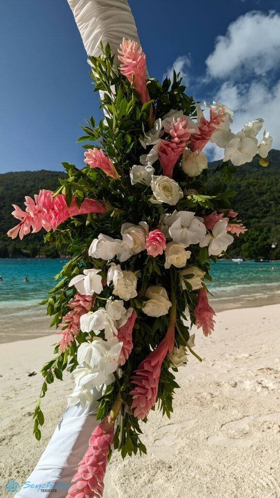 Fehér és rózsaszín virágokból, zöld levelekből álló boldogságkapu dísz Port Launay öbölnél.