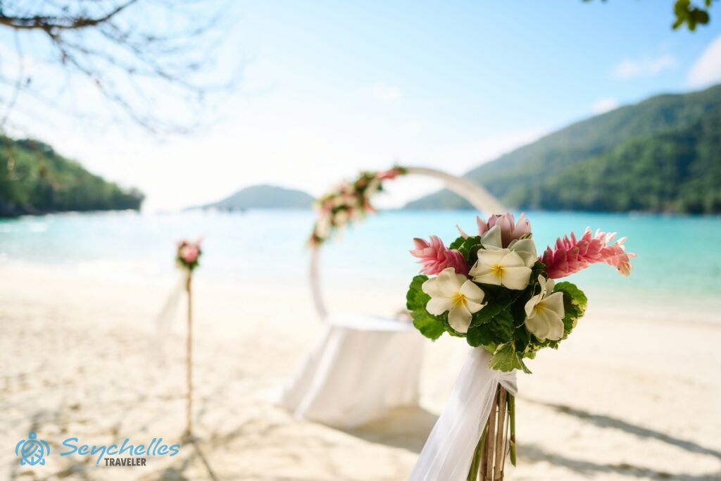 Virágcsokor a bevonuló folyosó egyik oszlopán, a háttérben az esküvői asztal és a gyűrű alakú boldogságkapu.