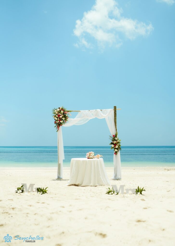 Esküvői dekoráció asztallal, szögletes boldogságkapuval, rózsával, frangipánival és gyömbér virággal Baie Lazare parton.