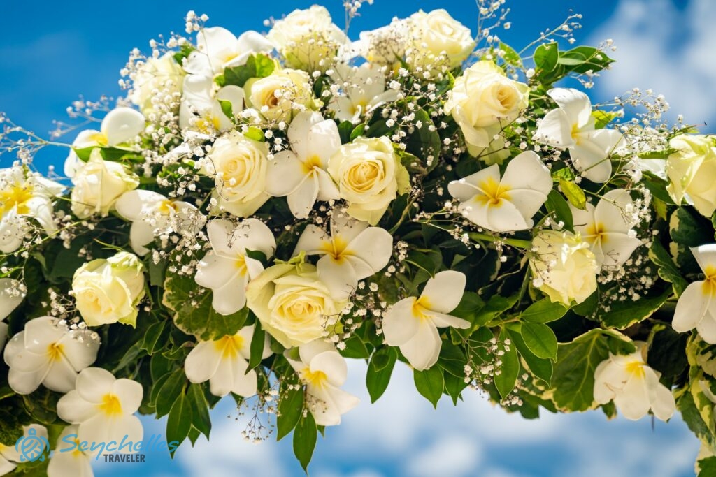 Világos sárga rózsákból, fehér frangipániból és rezgőből készült boldogságkapu dekoráció Baie Lazare tengerparton, Mahén.