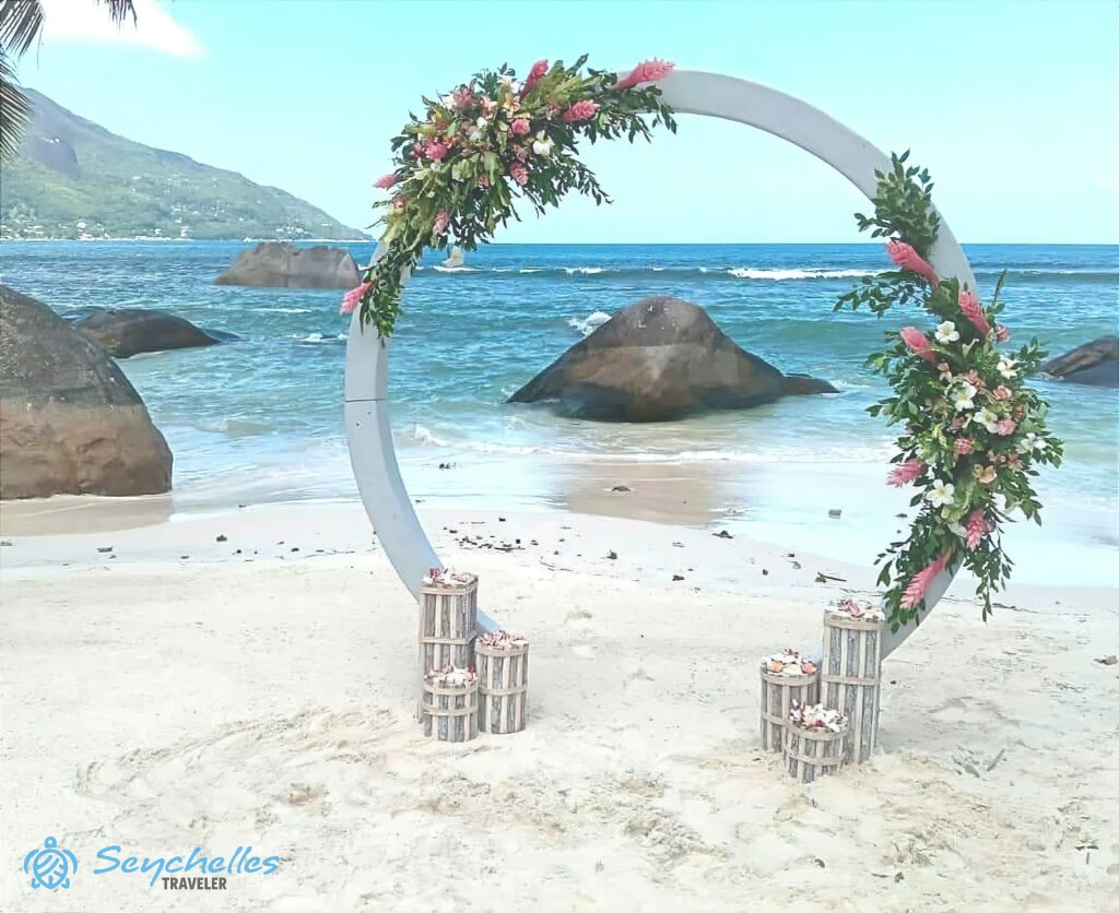 Gyűrű alakú boldogságkapu két nagy, trópusi virágokból kötött dísszel, Mahé szigeten.