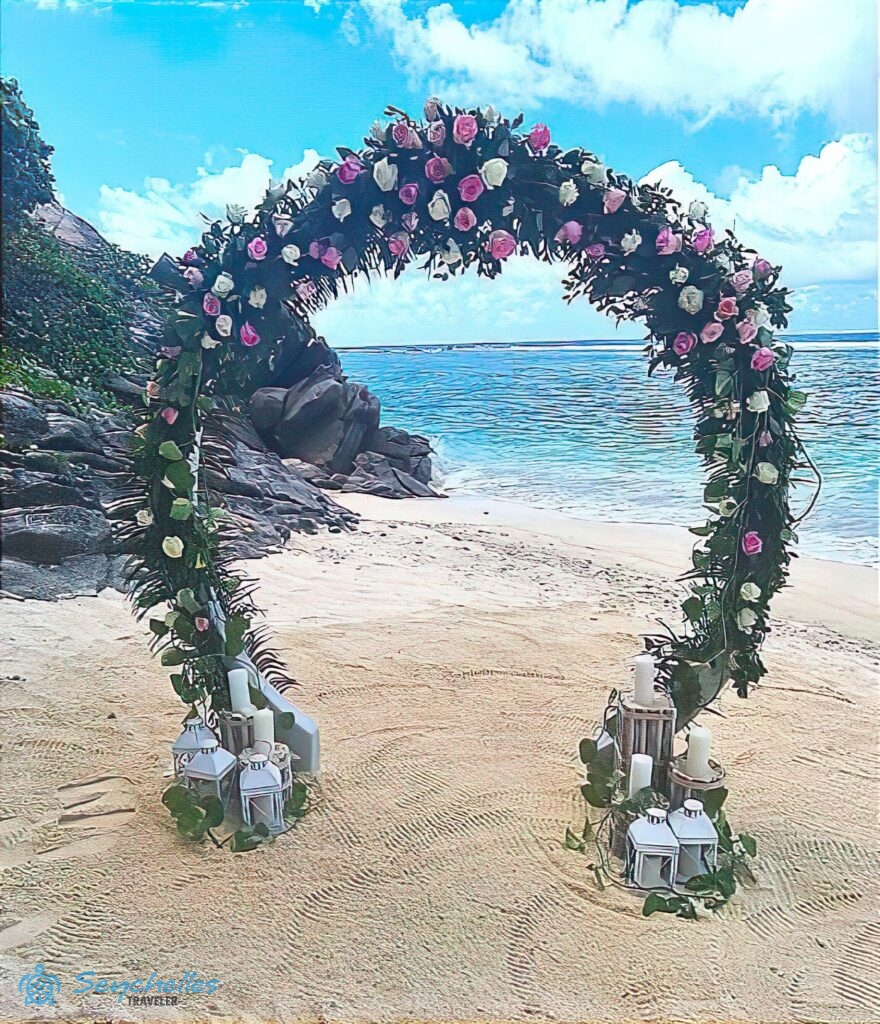 Rózsaszín és fehér rózsákkal, valamint zöld ágakkal sűrűn befont gyűrű alakú boldogságkapu, a lábánál gyertyákkal, Mahén.