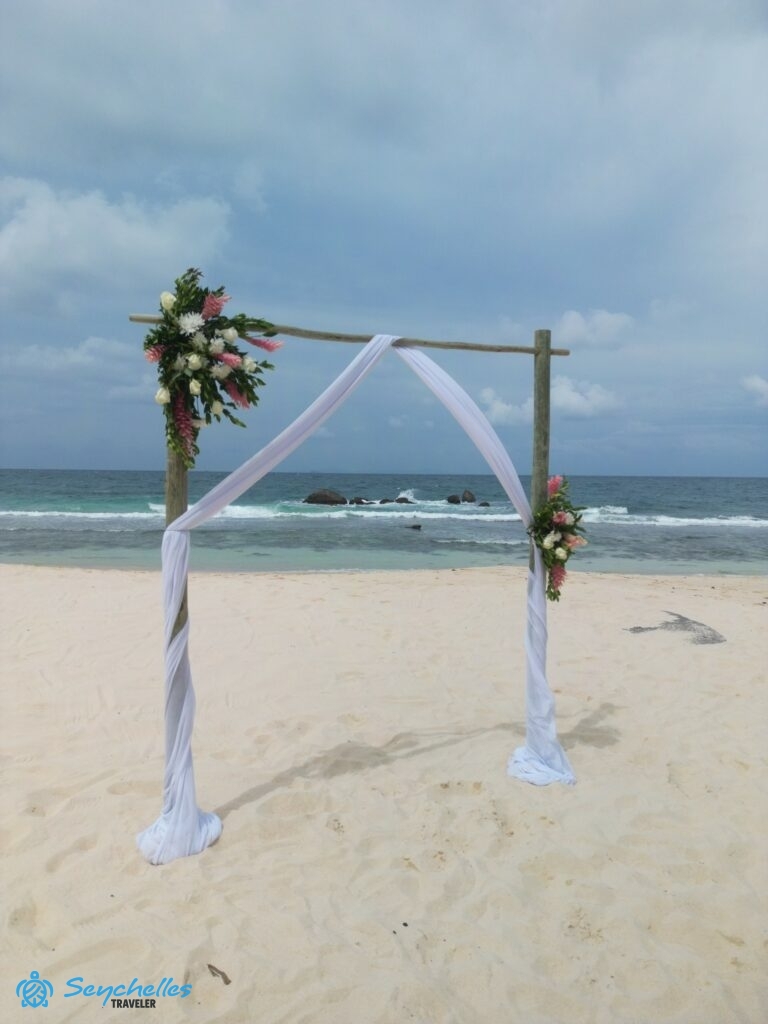 Két fehér és rózsaszín virágdísszel dekorált szögletes boldogságkapu North-East Point-on, Mahén.