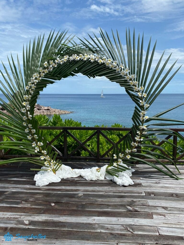 Gyűrű alakú boldogságkapu pálmalevélből és fehér frangipáni virágokból Praslin-en.