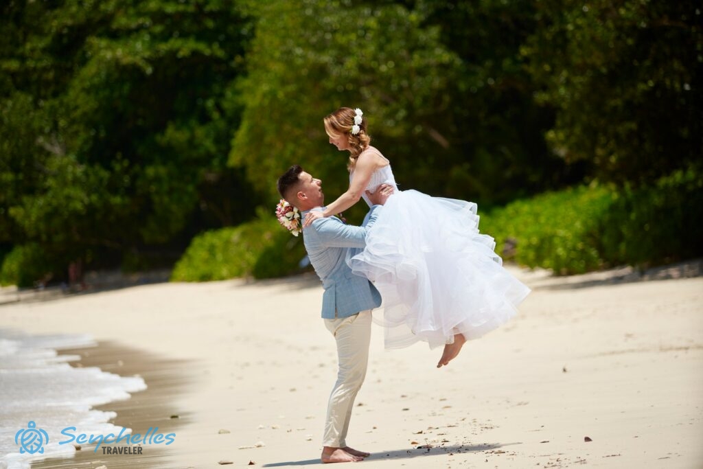 A vőlegény magasba emeli a menyasszonyt Anse Louis esküvő helyszín homokos tengerpartján.