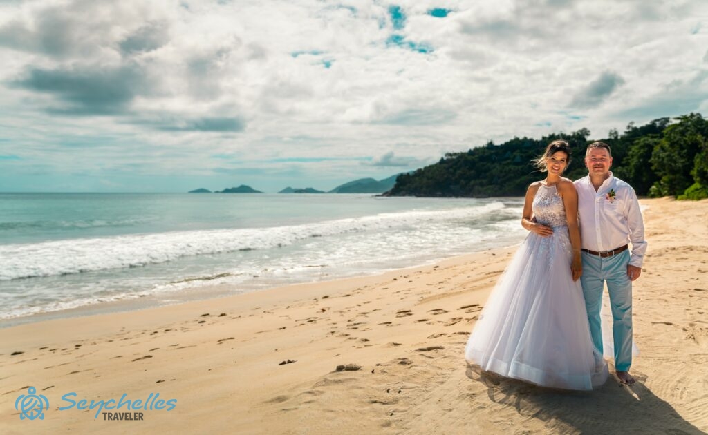 Házaspár áll a tengerparton a délutáni napfényben Anse Louis esküvői helyszínen.