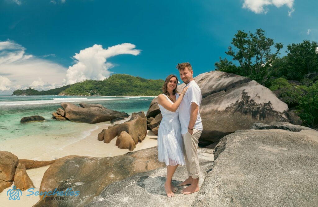 A fiatal házaspár a gránitsziklákon áll Baie Lazare tengerparton Mahén.