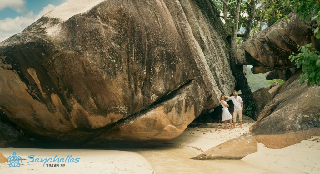 A fiatal pár Baie Lazare hatalmas gránitszikláinak egyikéhez támaszkodva áll Mahén.