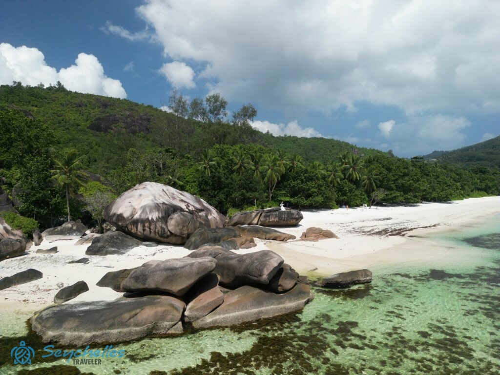 Drónfelvétel az óceán felől a párról, amint Roche Copra sziklán áll Baie Lazare tengerparton, Mahén.
