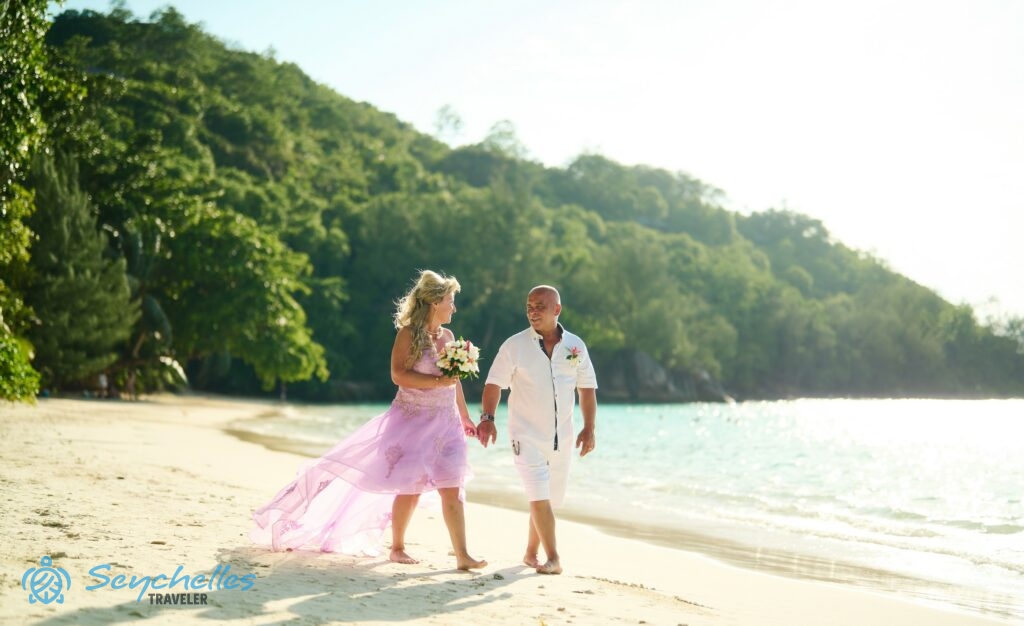 A friss házasok Port Launay öböl homokos partján sétálnak, az óceánon megcsillan a délutáni nap fénye.