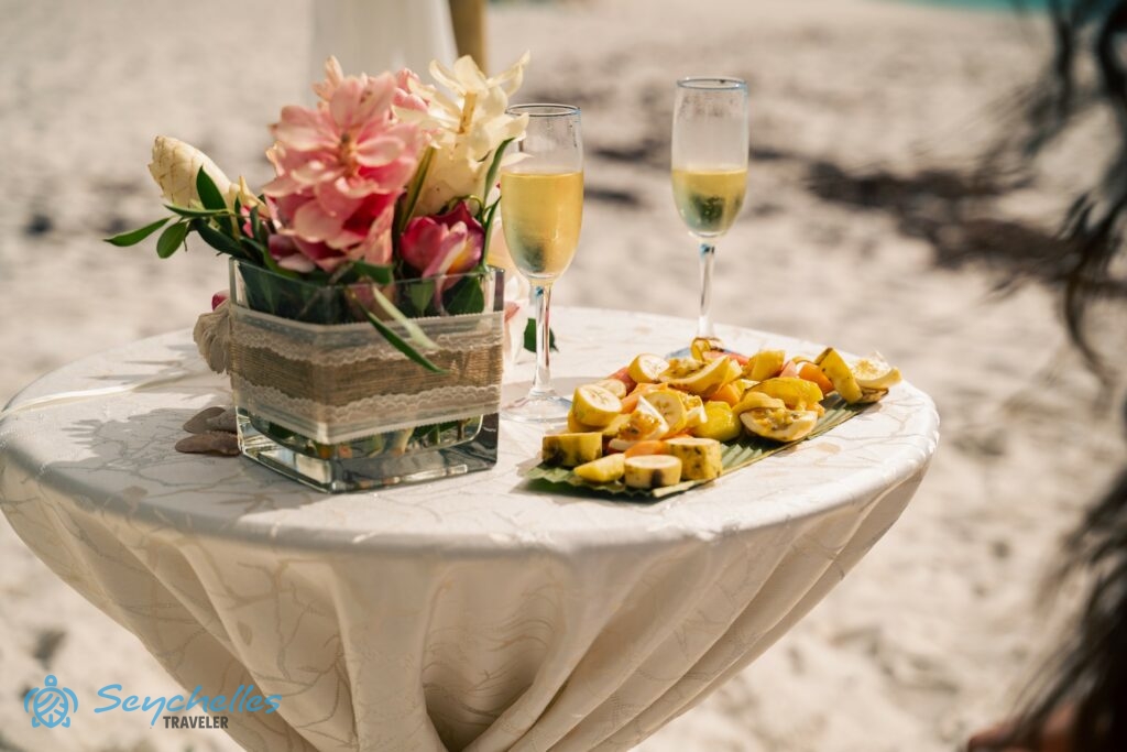 Asztali dekoráció, 2 pohár habzóbor és gyümölcstál az esküvői asztalon Anse Georgette tengerparton.