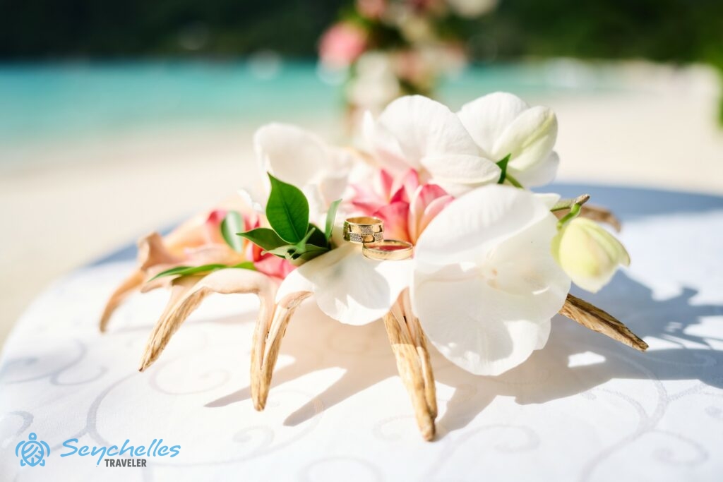 Orchidea és frangipáni virágokkal díszített tengeri csigaház gyűrűtartó karikagyűrűkkel Port Launay öbölben, Mahén.