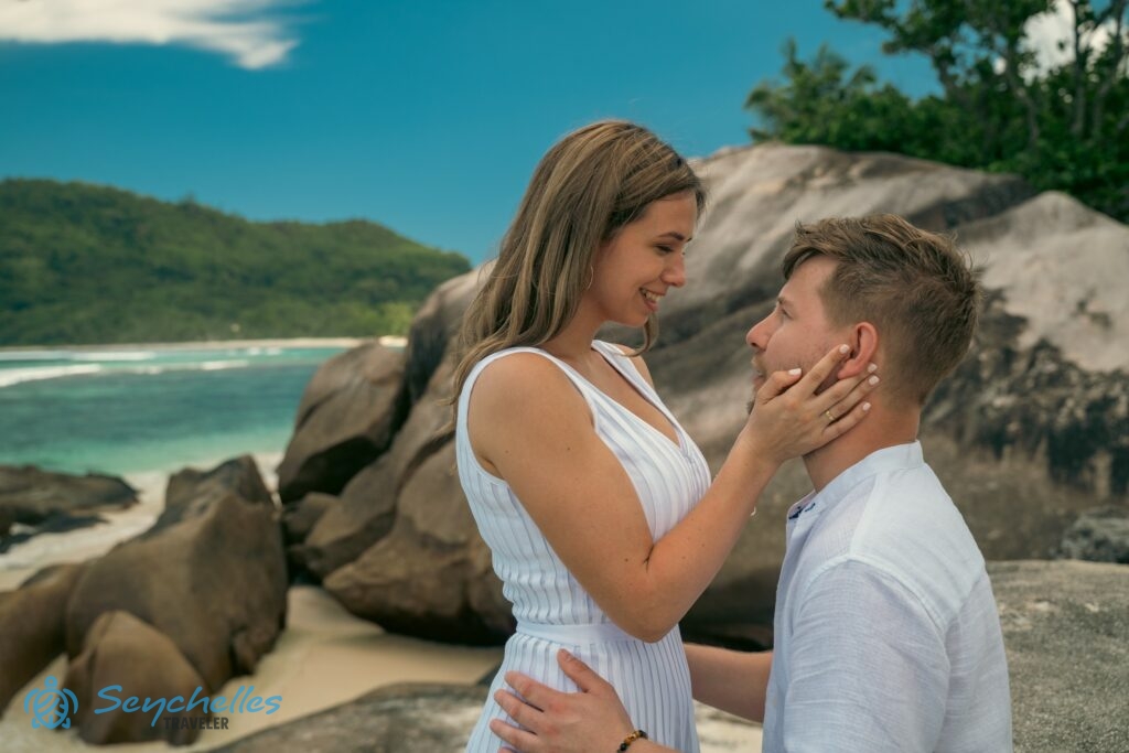 Az ifjú feleség férje arcát kezei között fogja, és mosolyogva néz rá Baie Lazare szikláinál.