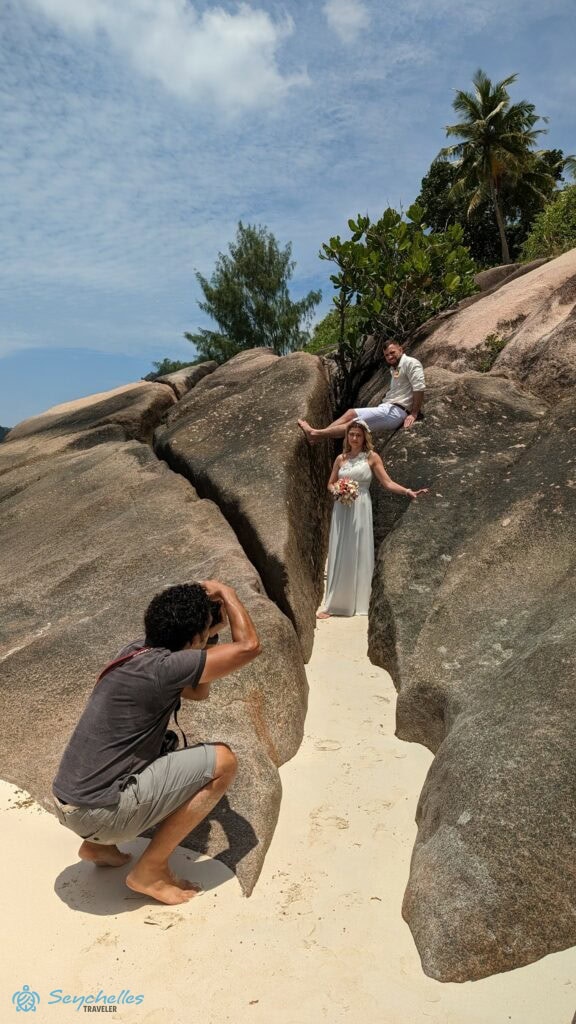 A szikál közötti homokos ösvényen álló párról esküvői fotók készülnek Baie Lazare parton.
