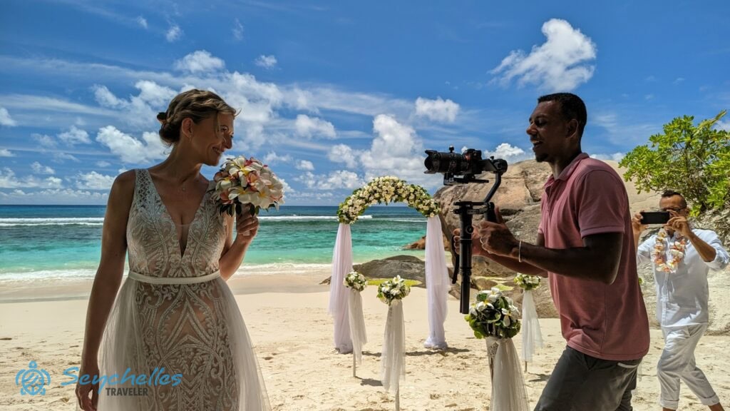 Közeli kép a mosolygó menyasszonyról az esküvői videózás közben Baie Lazare tengerparton.