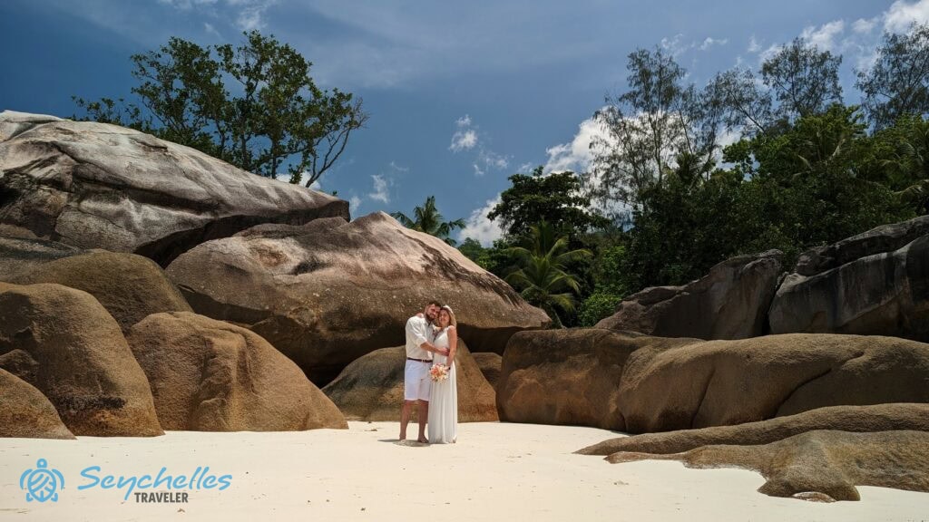 Esküvői werkfotó az ifjú párról Baie Lazare sziklái között a homokban állva.
