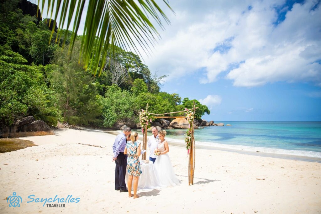 Az ifjú párral szemben, az anyakönyvvezető mellett állva mondja Réka a magyar hivatalos esküvői beszédét Anse Louis parton.