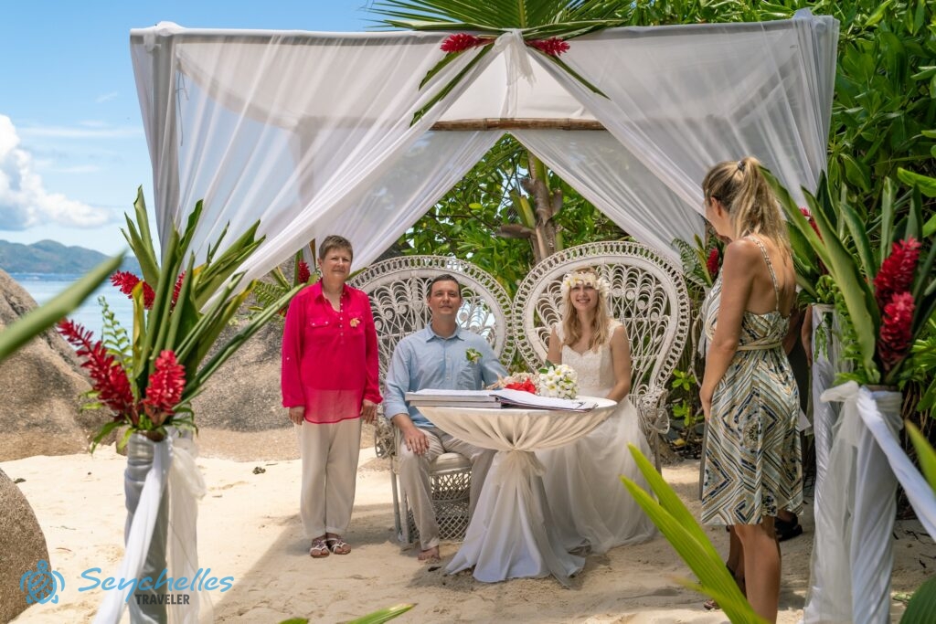 A pavilon alatt, pávaszékekben ülve várja a fiatal pár a magyar hivatalos esküvő kezdetét Anse Source D'Argent parton.