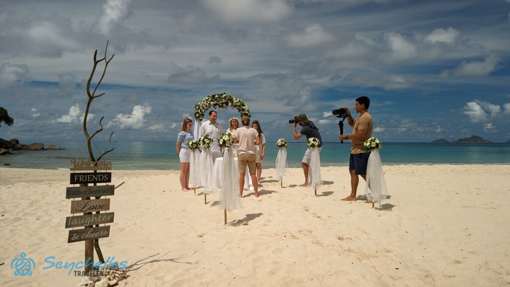 A résztvevők és a magyar nyelvű szimbolikus szertartáshoz feldíszített helyszín Anse Louis tengerparton, háttérben az óceán.