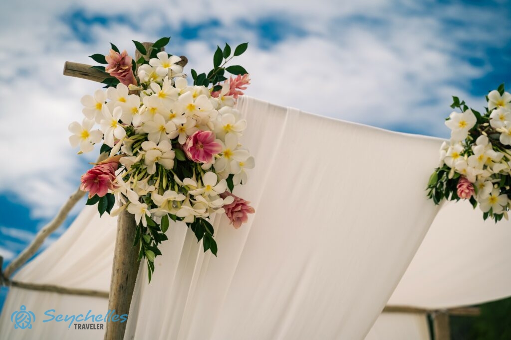 Az esküvői pavilont díszítő frangipáni és más trópusi virágokból álló virágcsokor, Anse Georgette tengerparton.