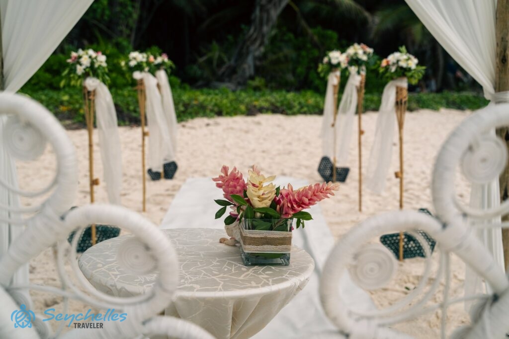 Az esküvői asztal és a bevonuló folyosó a jegyespár székei mögül fényképezve Anse Georgette tengerparton.