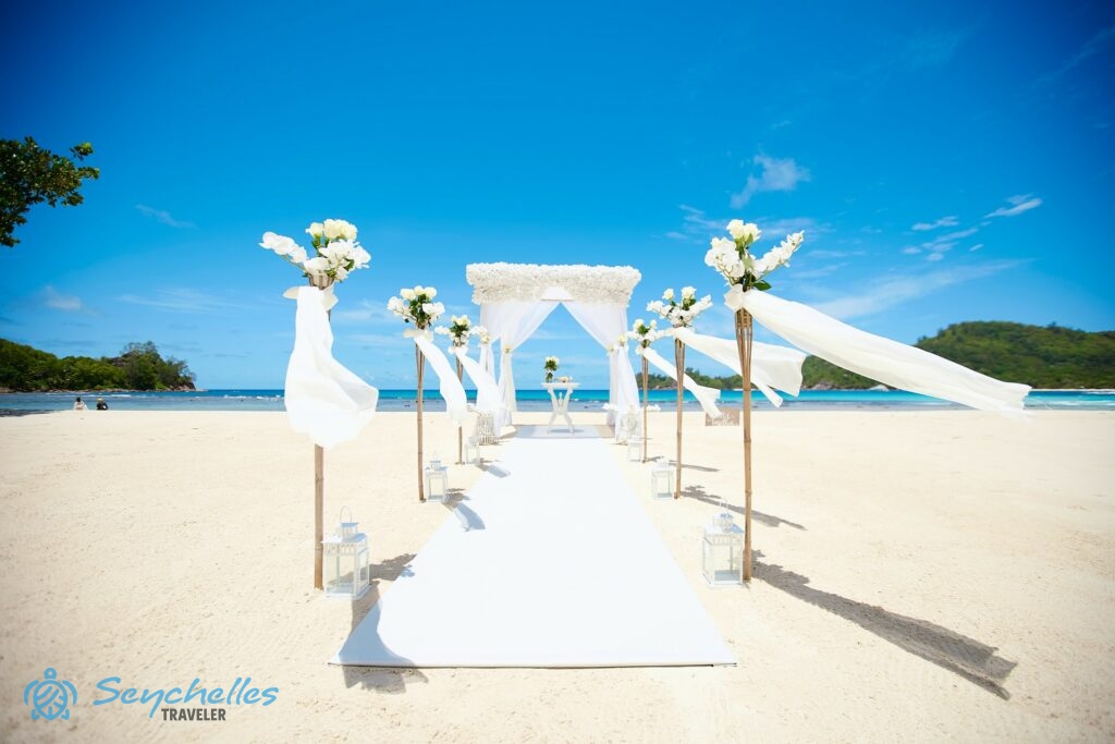 Fehér szőnyeggel leterített, 6 magas bambusz oszloppal szegélyezett bevonuló folyosó, esküvői pavilon fehér virágokkal.