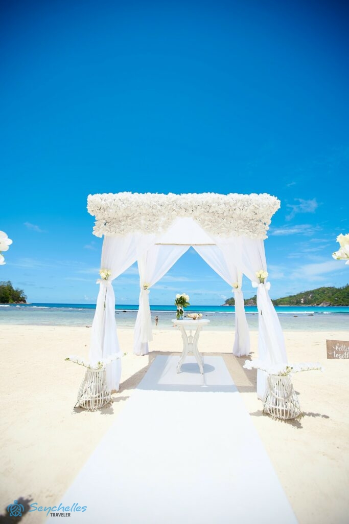 A bevonuló folyosó fehér szőnyege, az esküvői asztal és a fehér művirágokkal díszített esküvői pavilon.