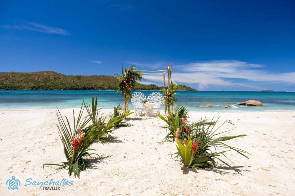 Pálmalevelekkel és trópusi virágokkal díszített bevonuló folyosó, fátyol nélküli esküvői pavilon 2 pávaszékkel.