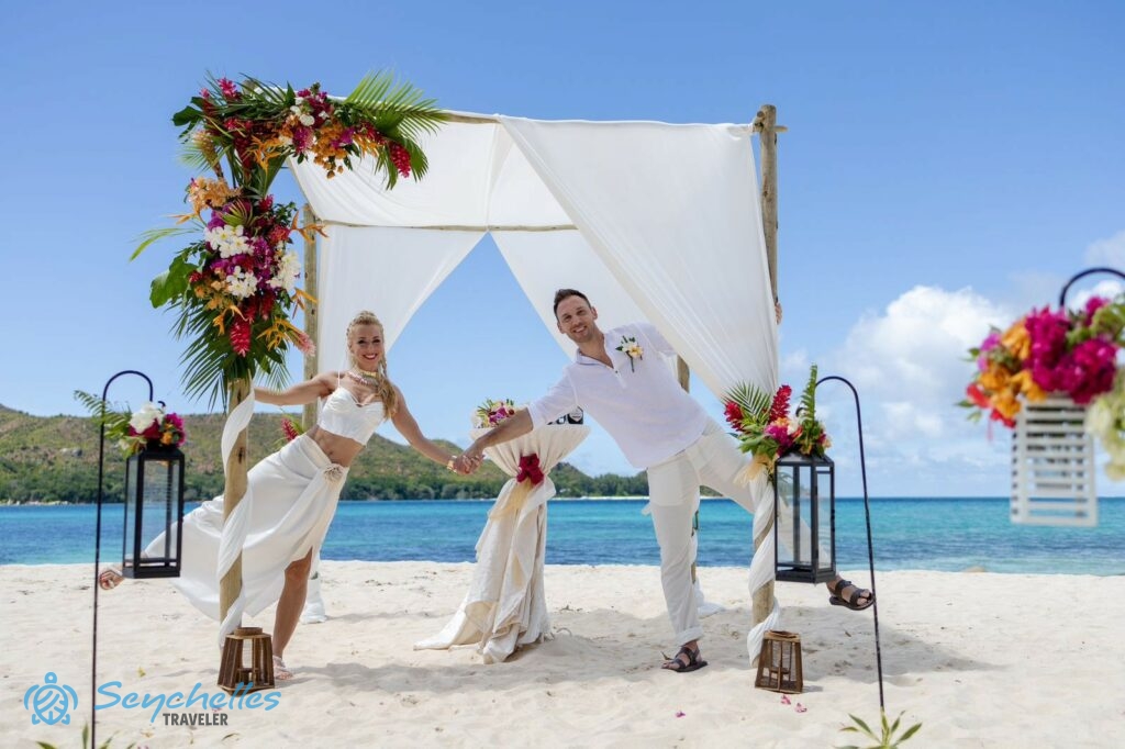 Lámpásokból álló bevonuló folyosó és színes trópusi virágokkal díszített esküvői pavilon, az ifjú párral Praslin-en.