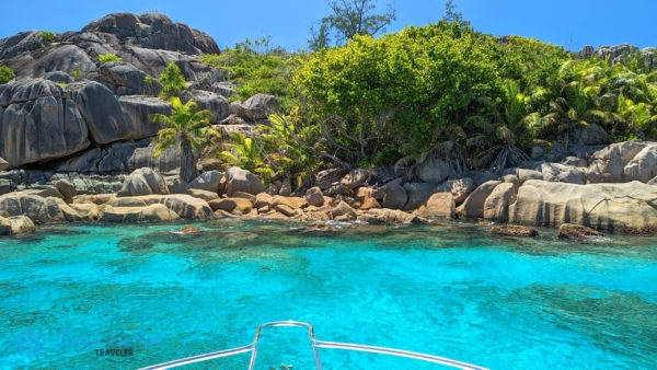 Gránitsziklás part trópusi növényzettel Grande Soeur-szigeten, az előtérben a türkiz színű óceánnal.