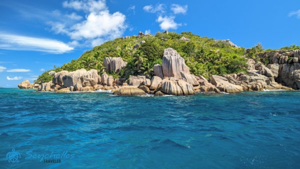 Petite Soeur déli csücskét szegélyező gránitsziklák, a háttérben a sziget trópusi növényzete.