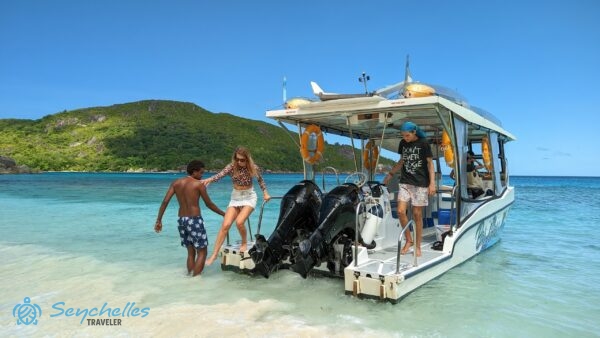 A hajó kapitánya az egyik látogatónak segít a partraszállásban, Anse du Riz parton.