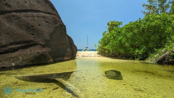 Anse Du Riz a sziget belseje felől fényképezve gránitsziklával és a vízen katamaránnal.
