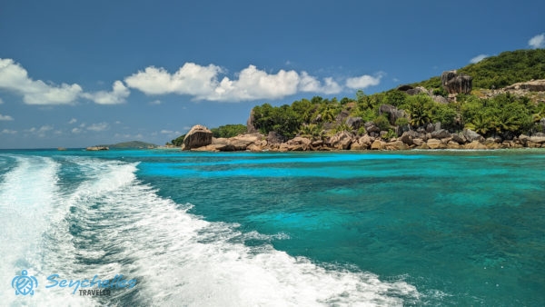 Parti sziklák a hajó nyomában hullámzó tengerrel La Digue-szigetnél.