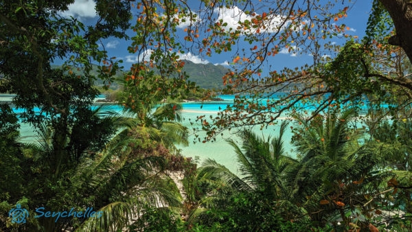 Trópusi növényzet és a mögötte elterülő kristálytiszta óceán, a háttérben Round és Mahe szigetek.