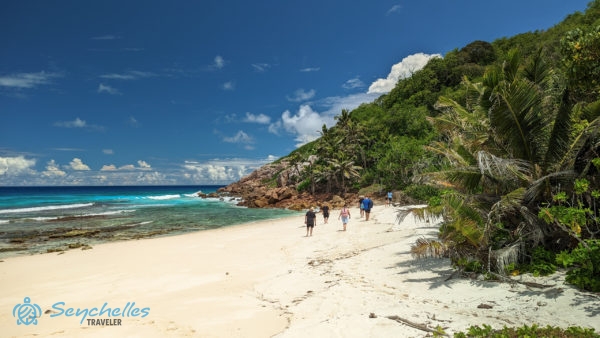 Látogatók sétálnak Aride-sziget enyhén hullámos, homokos tengerpartján, alacsony vízállásnál.